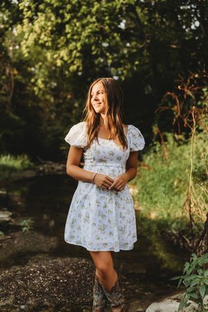senior girl in creek sun hitting her face white dress brown hair