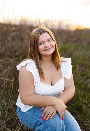 senior girl pink nails sunset kneeling blue jeans white shirt