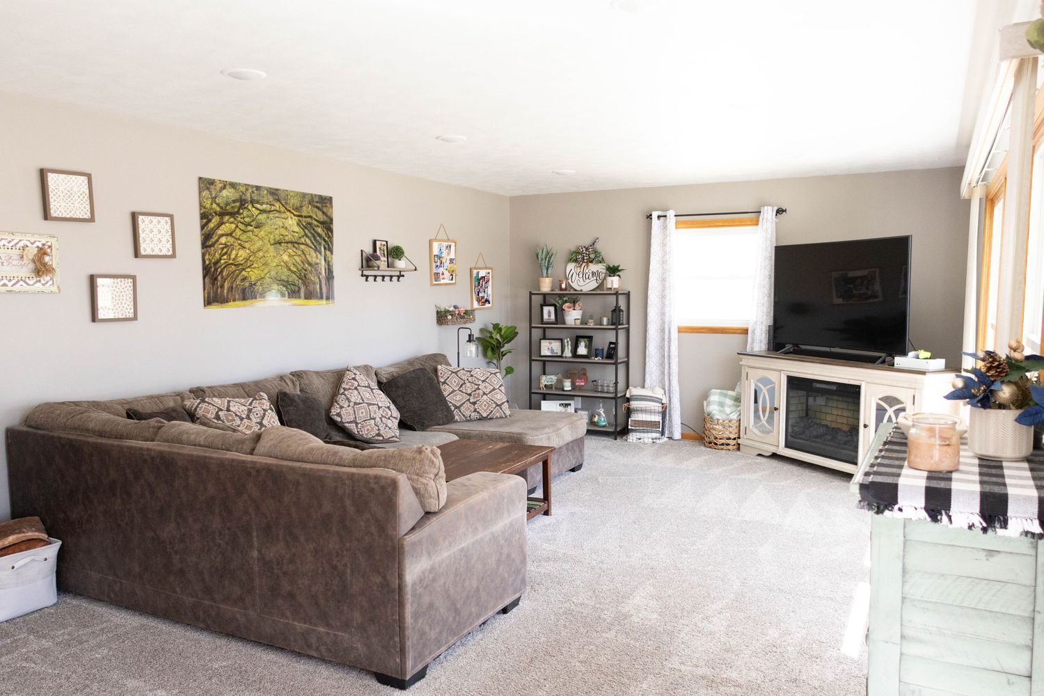 Spacious living room with brown sectional sofa and natural lighting from multiple windows.
