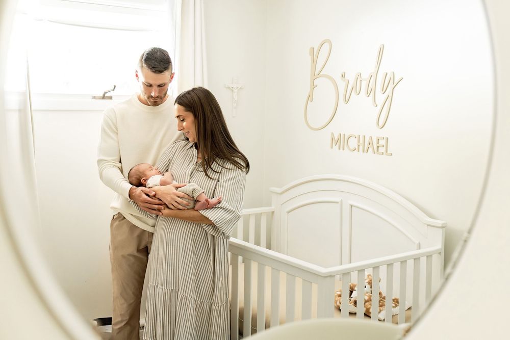 A series of soft, neutral-toned nursery photos showing parents with a newborn baby in a minimalist setting.