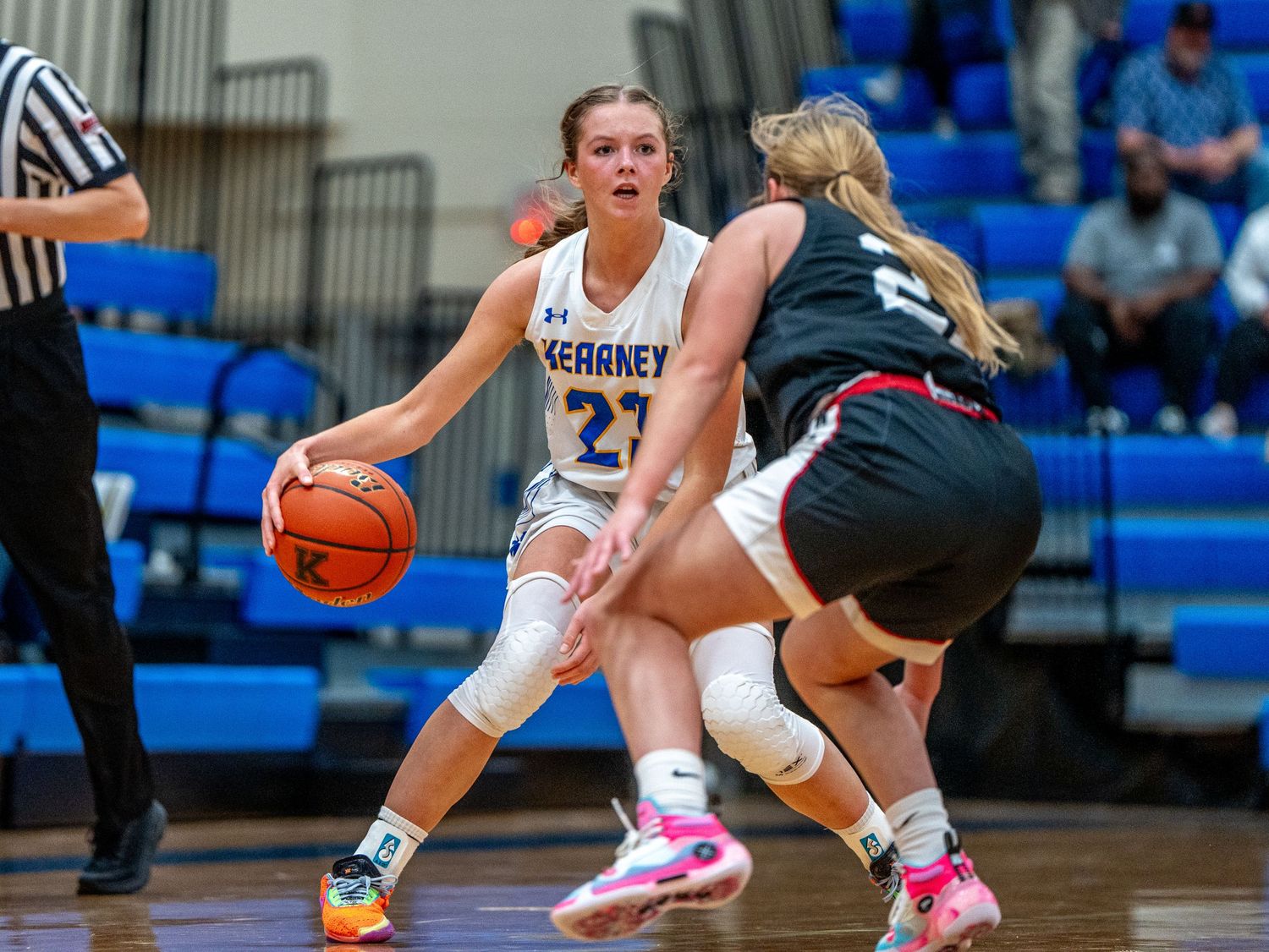 Basketball player dribbles past defender during intense game action on indoor court.
