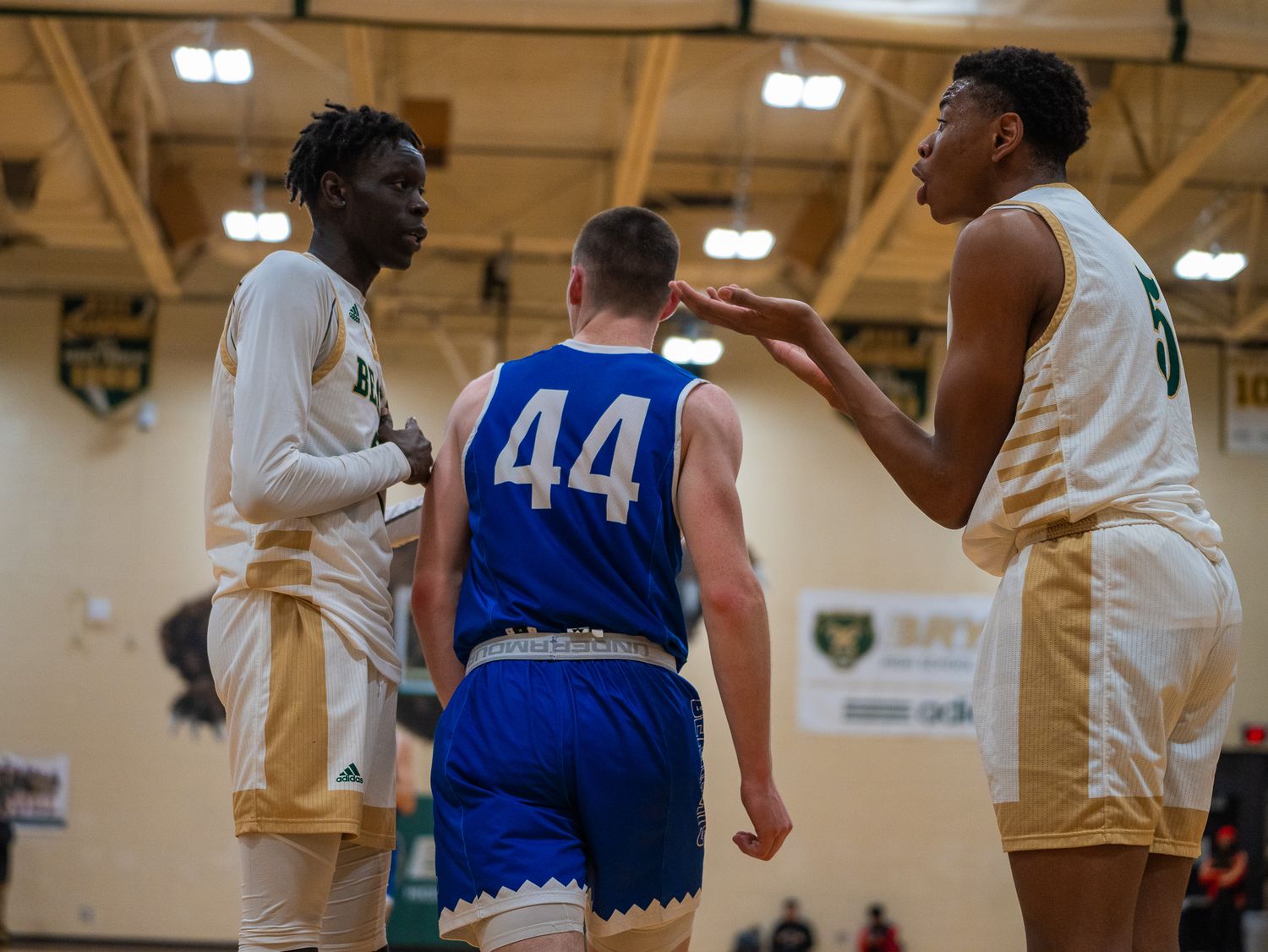 Basketball players from opposing teams interact during game with player wearing number 44 in blue jersey.