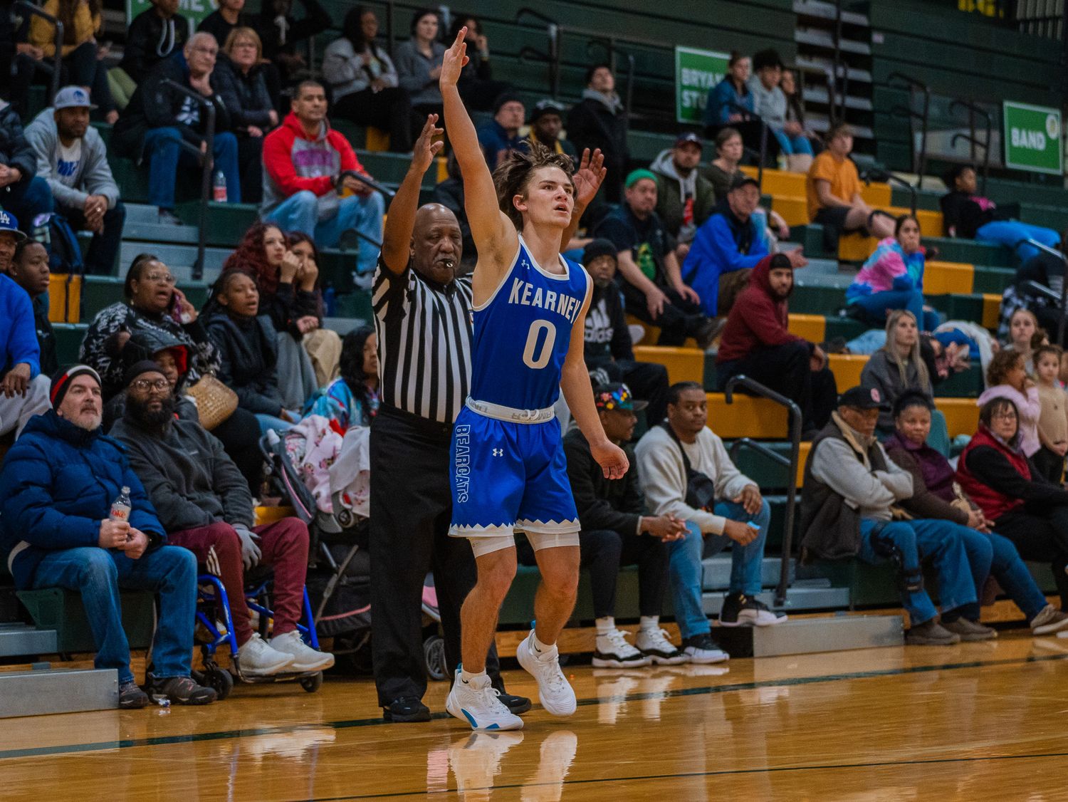 Basketball player in blue jersey number 0 shoots a three pointer during a game.