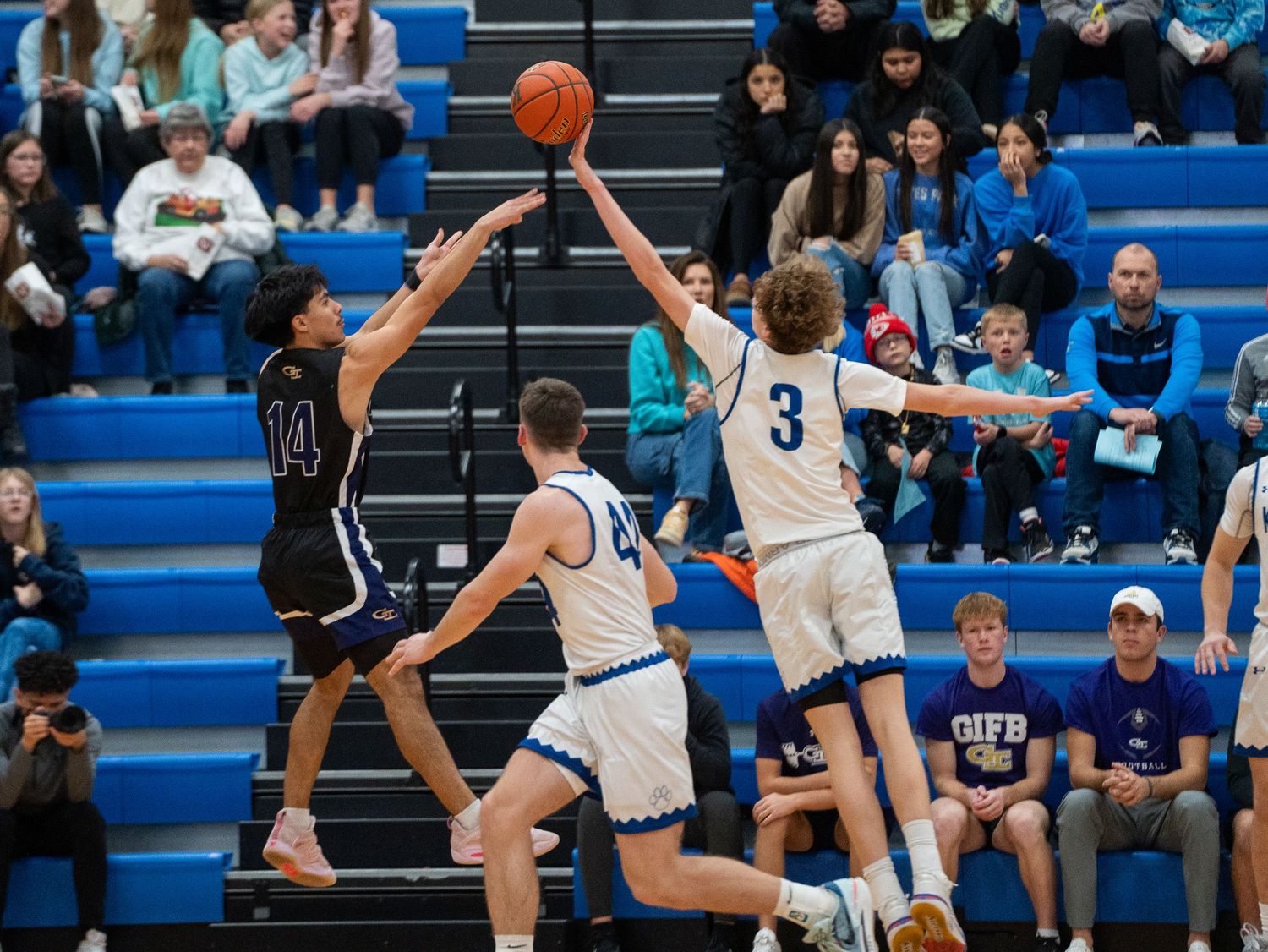 Players leap high to contest for the basketball during competitive game action.