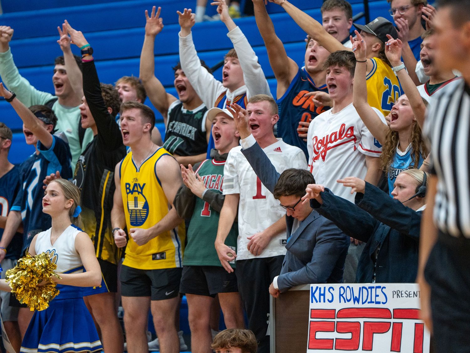 Enthusiastic student section cheers during basketball game with ESPN sign visible.
