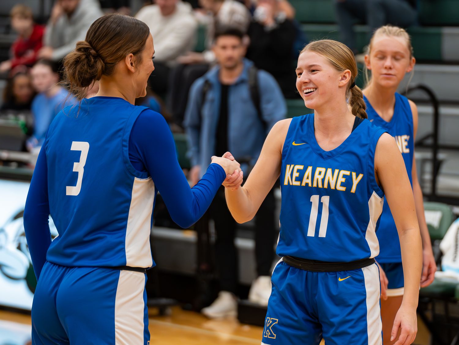 Teammates share a celebratory moment during basketball game in blue uniforms.