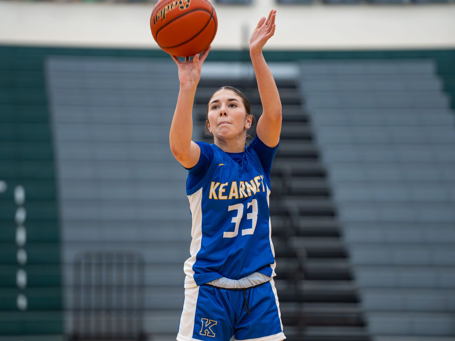 Player in blue Kearney jersey takes jump shot during basketball game.