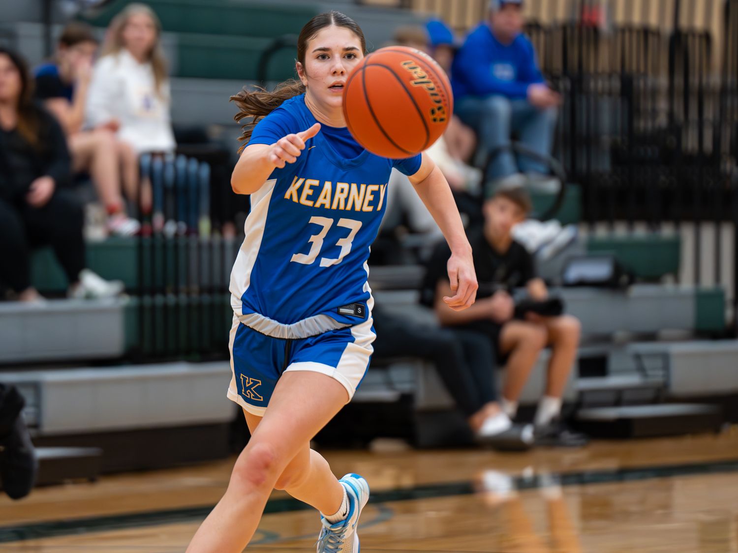 Player in blue Kearney jersey number 33 dribbles basketball during game action.