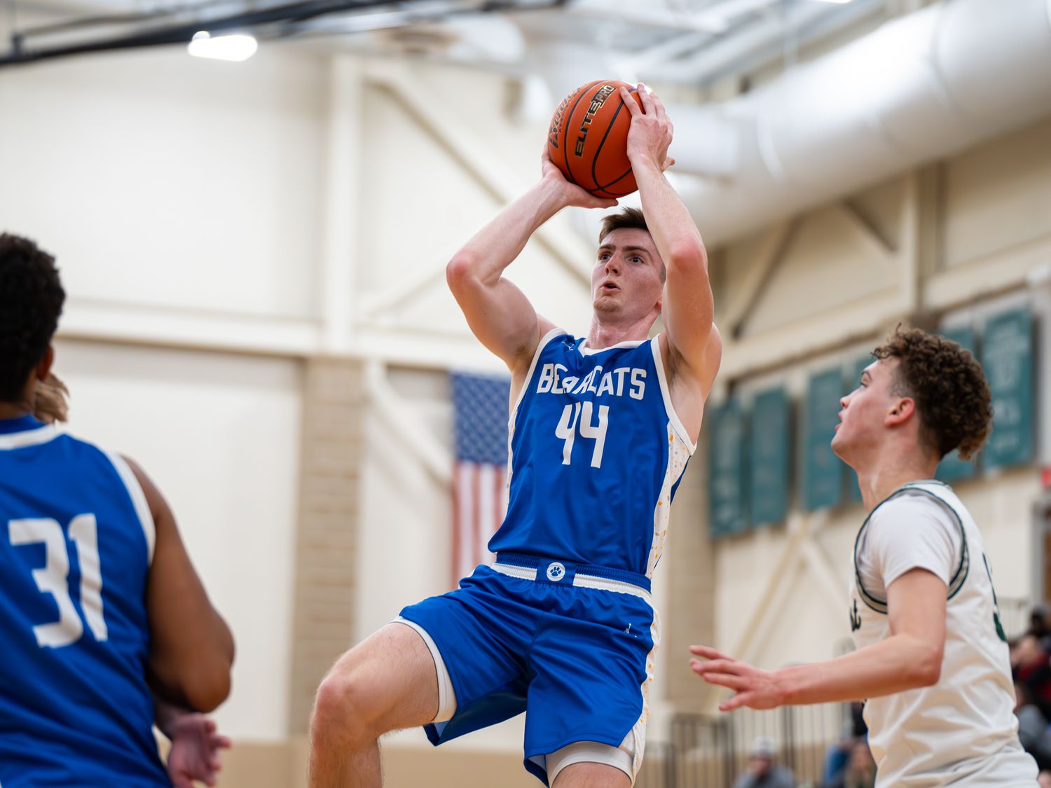 Basketball player in blue jersey 44 leaps for shot while defender tries to block.