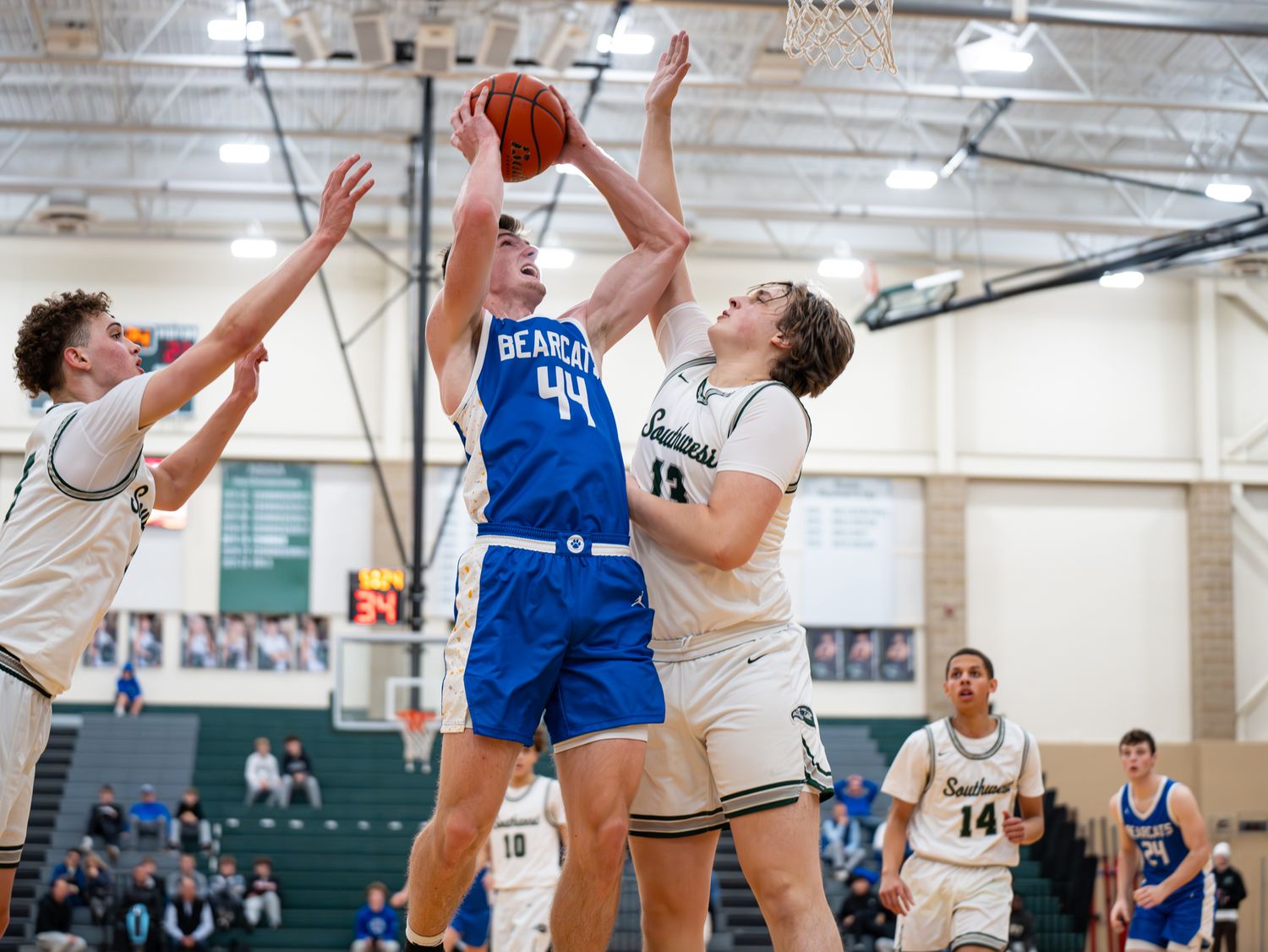 Basketball player in blue jersey shoots over defenders during intense game action.