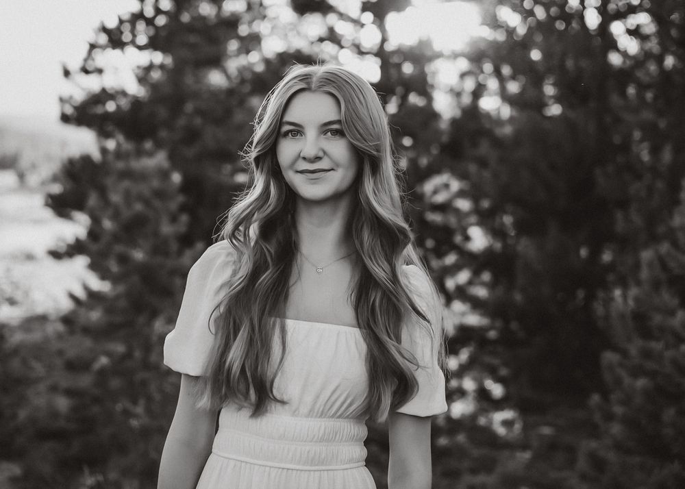 Black and white portrait of person in white dress outdoors.