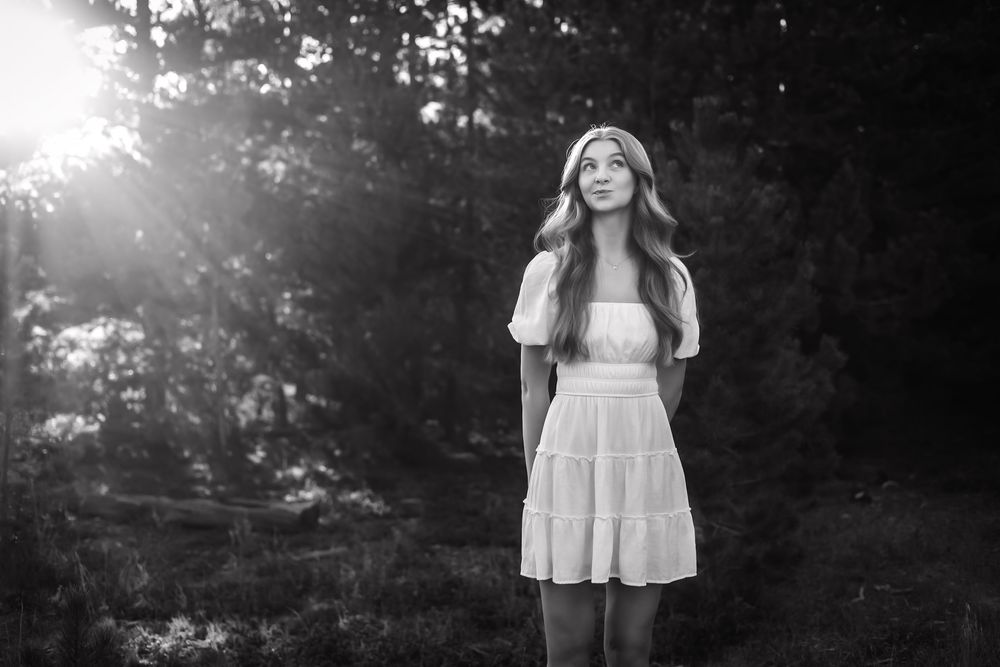 Black and white photo of someone in white dress against natural backdrop.