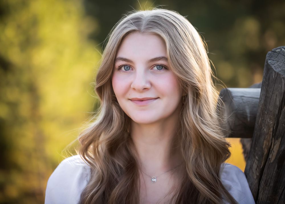 Portrait shot in natural lighting against autumn foliage background.