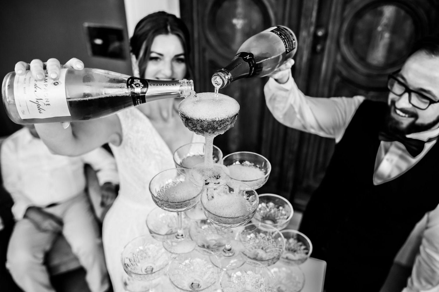 Couple pouring champagne into a tower of elegant coupe glasses. Organized wedding by MyCastleWedding in Dresden/Germany
