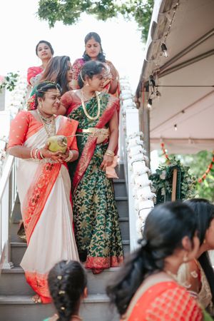 Women in traditional Indian sarees descend decorated stairs during a vibrant South Asian wedding ceremony.