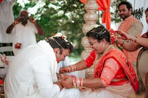Bride and groom exchange garlands during a traditional Indian wedding ceremony outdoors.