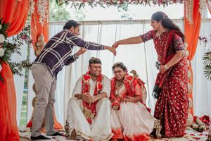 Family members bless the bride and groom seated under a floral mandap at a traditional Indian wedding.