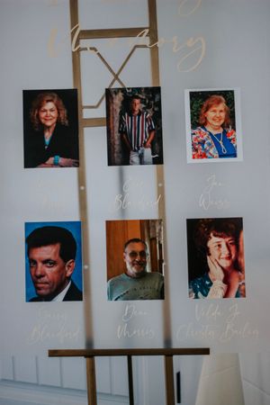 Memorial display on an easel featuring six portrait photos of loved ones with handwritten names in white calligraphy.