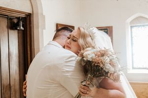 Bride and groom share a tender kiss at the altar, bride holding a rustic dried flower bouquet in a white wedding dress.