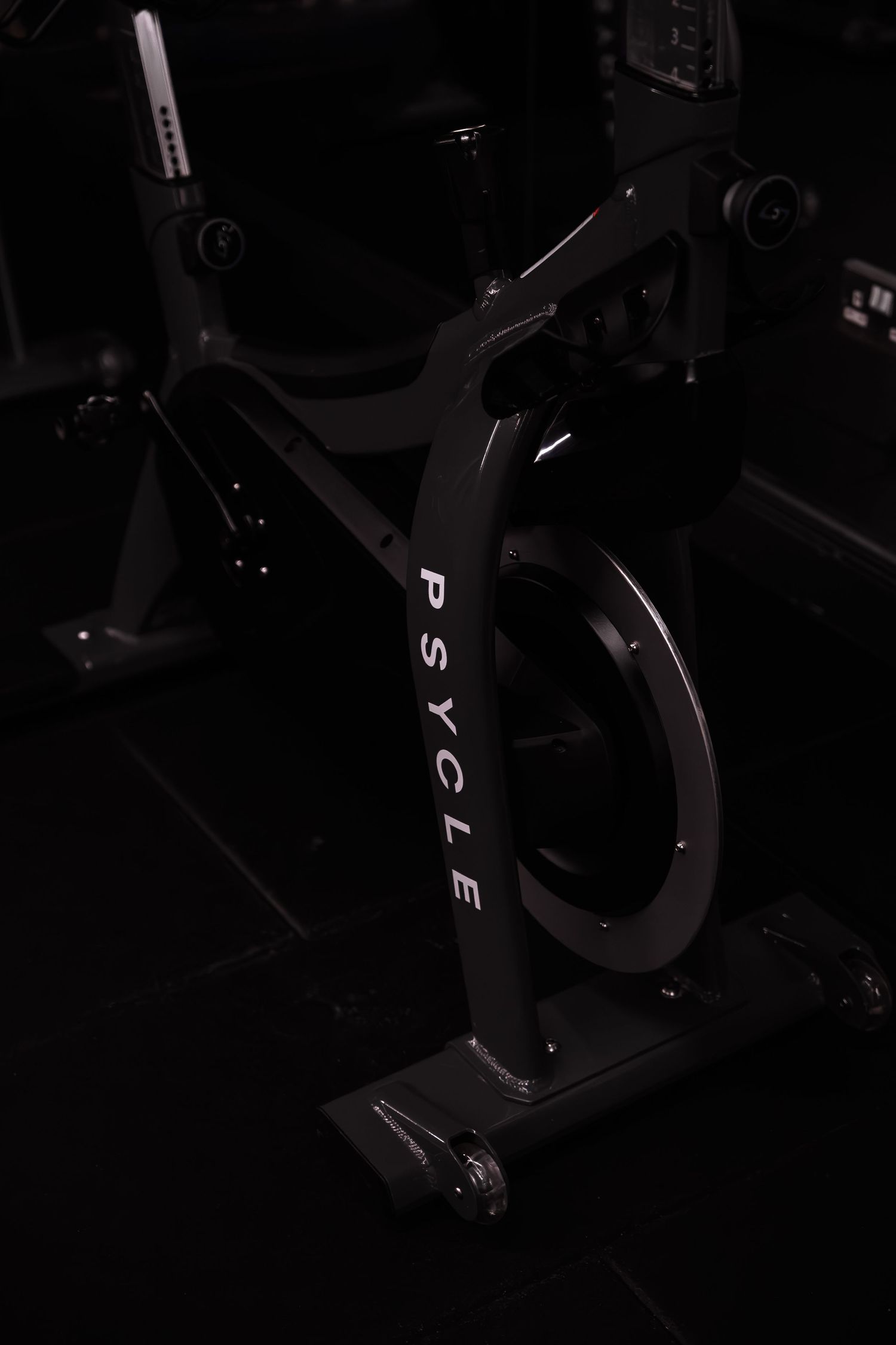 Black Psycle indoor cycling spin bike in a dark studio gym setting.