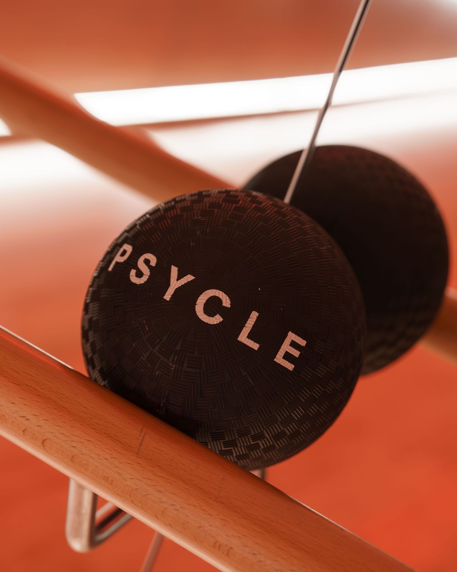 Close-up of Psycle branded black weighted exercise balls on a wooden barre in an orange studio.