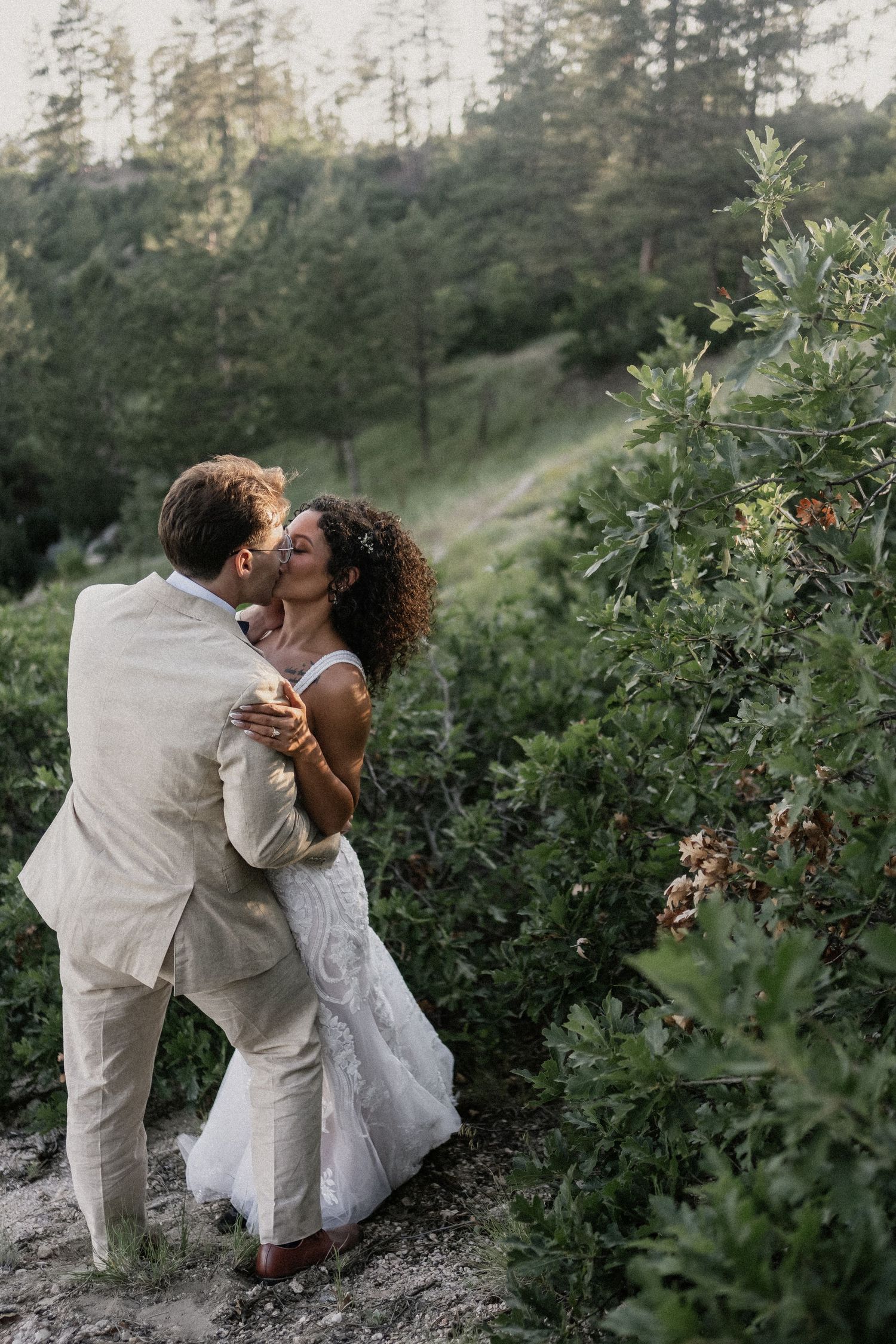 Playful moment captured at beach wedding ceremony under geometric gold arch with white floral arrangements.
