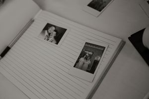 Open wedding guest book with black and white Polaroid photos on lined pages for memories.