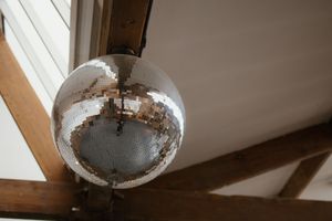 Shiny disco mirror ball hanging from wooden beam ceiling at wedding reception venue.