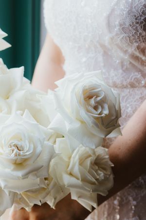 Bride in lace dress holding a bouquet of white roses.