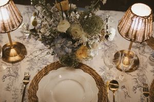 Elegant wedding table setting with floral centerpiece, gold cutlery, and rope charger plates.