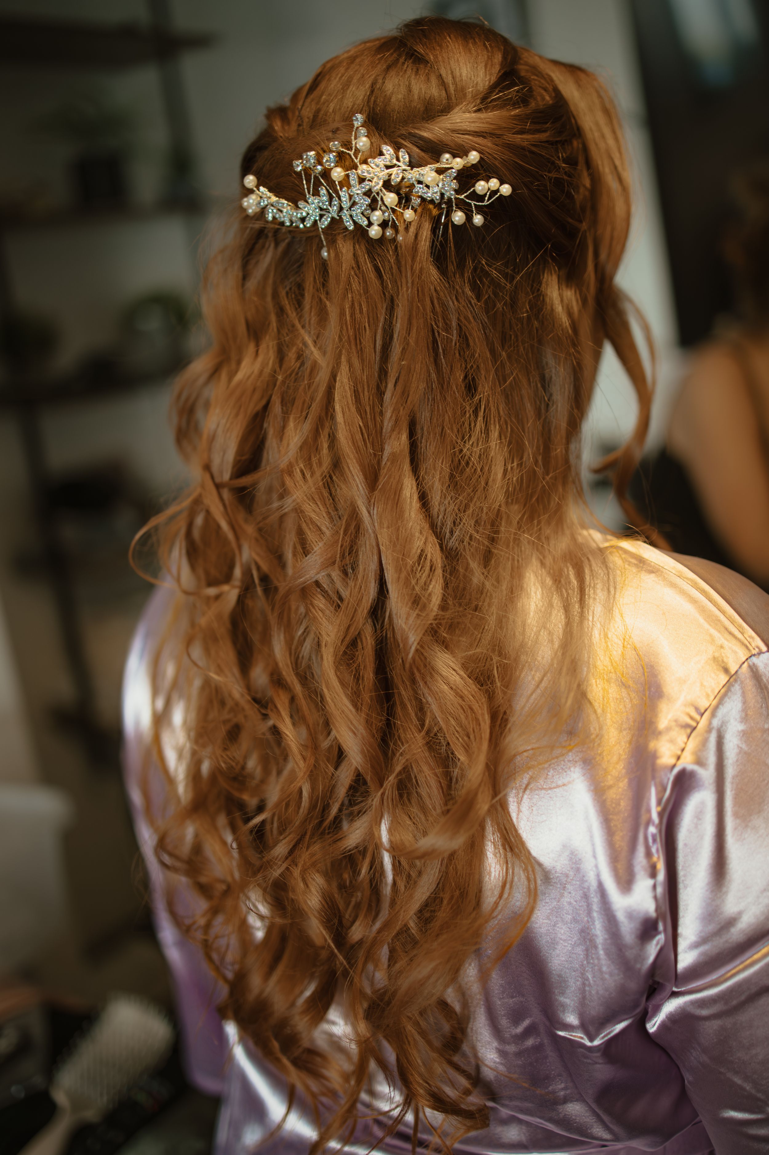 Back view of bride with long curly red hair and delicate floral hair piece.
