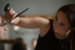 Professional makeup artist applying eye makeup to bride during wedding morning preparations.