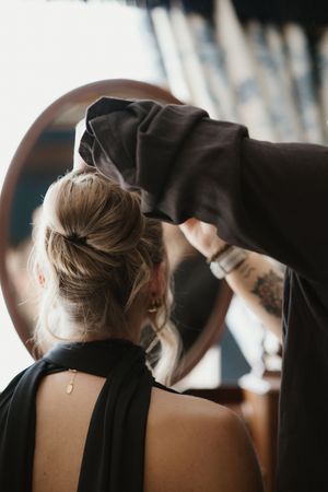 Hairstylist arranging an elegant updo bun with a black scrunchie.