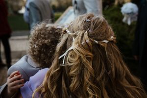 Back view of bridesmaids's half-up hairstyle adorned with delicate floral accessories at a wedding.
