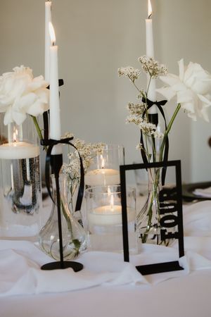 Black and white wedding table centerpiece with white candles, flowers, and table number four.