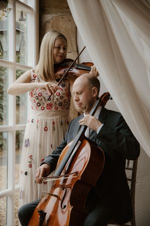 Violin and cello duo performing classical music at elegant wedding ceremony.