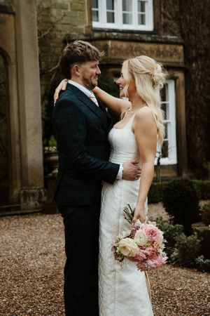 Bride and groom sharing romantic moment outside stone manor wedding venue.