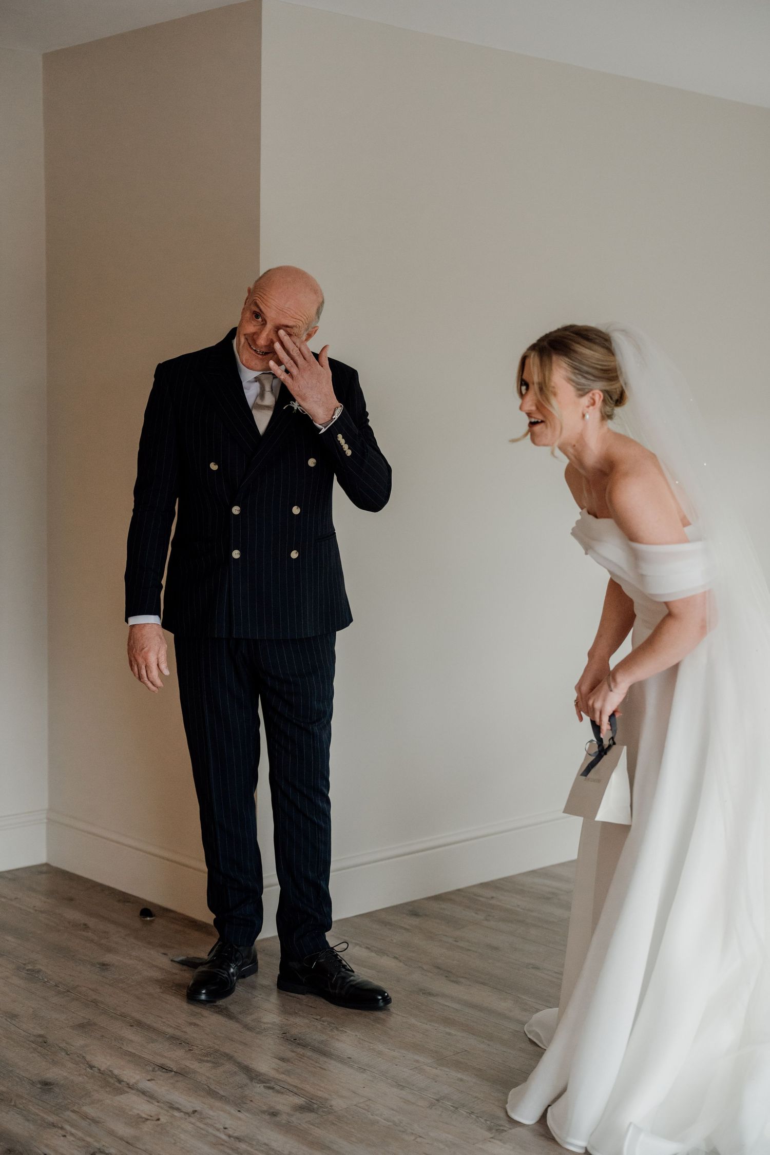 Emotional father wiping tears during first look moment before wedding ceremony at Quantock Lakes.