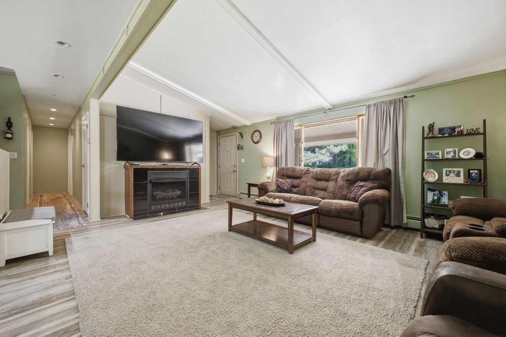Cozy living room featuring a fireplace, brown leather sofas, carpeted floors, and a wall-mounted flat-screen TV.