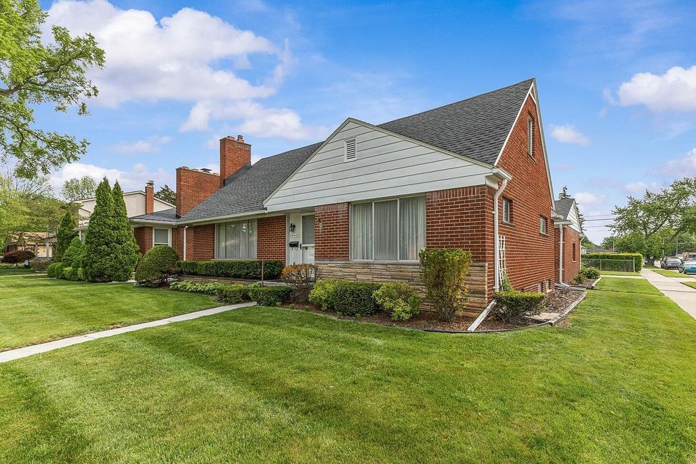 Charming brick ranch home with lush green lawn, manicured shrubs, and classic architectural details under a blue sky.