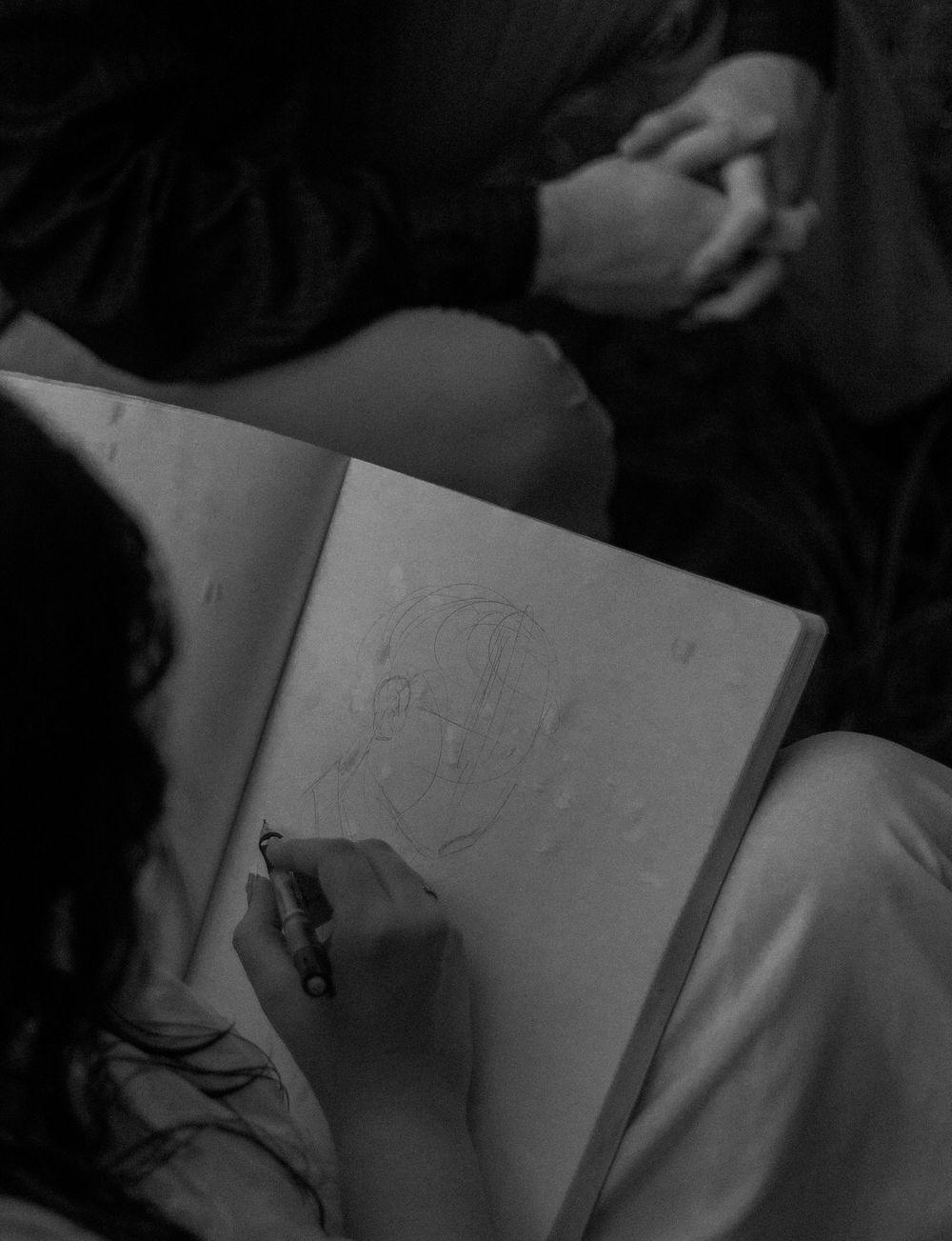 Artist sketching portrait in sketchbook in black and white photo.