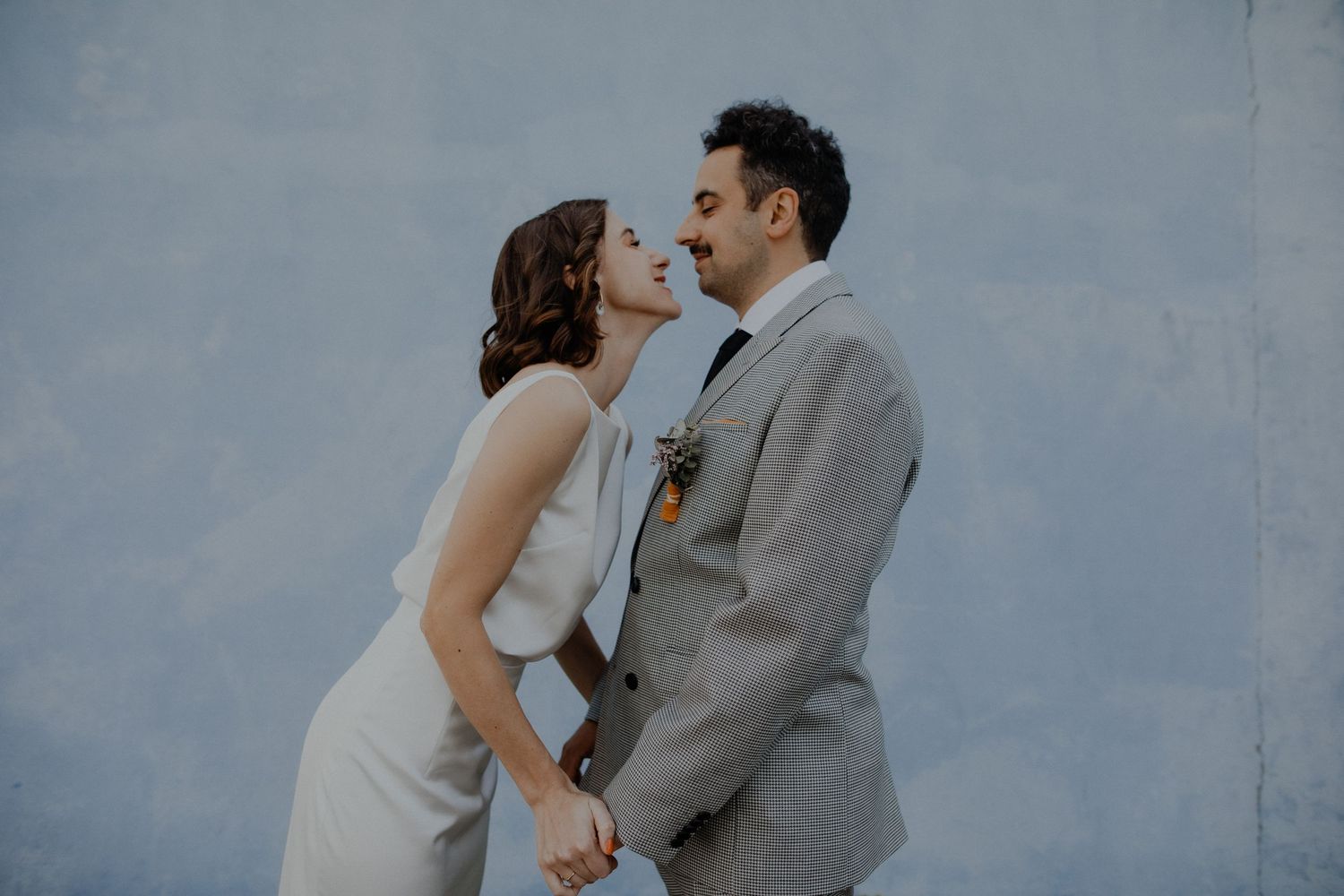 Couple sharing a romantic moment against a grey backdrop.