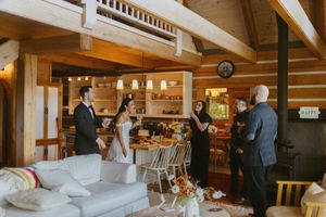 Bride and groom celebrate with guests in a rustic log cabin wedding reception with warm wooden interiors.