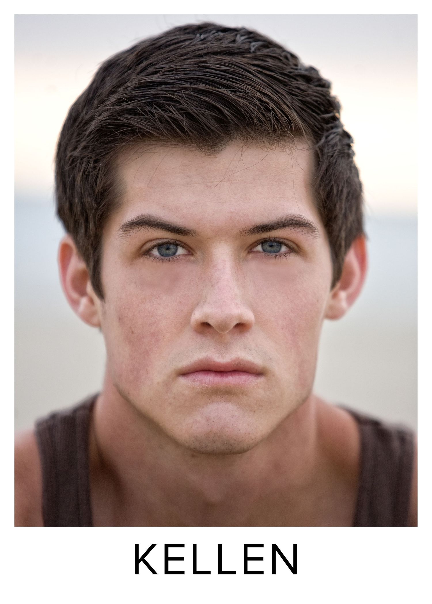 Close-up portrait of a young man named Kellen with dark hair and blue eyes against a blurred background.