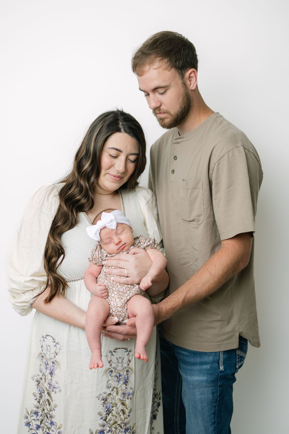 Young parents tenderly gazing at their newborn baby during a studio portrait session.