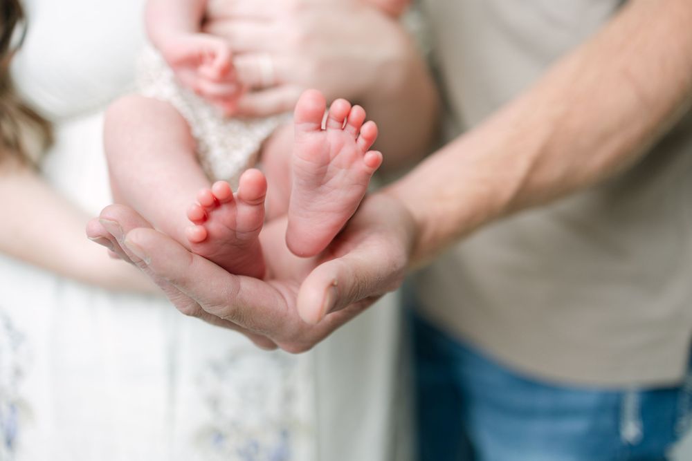 Parents cradling their newborn baby's tiny feet in their hands during a studio photo session.