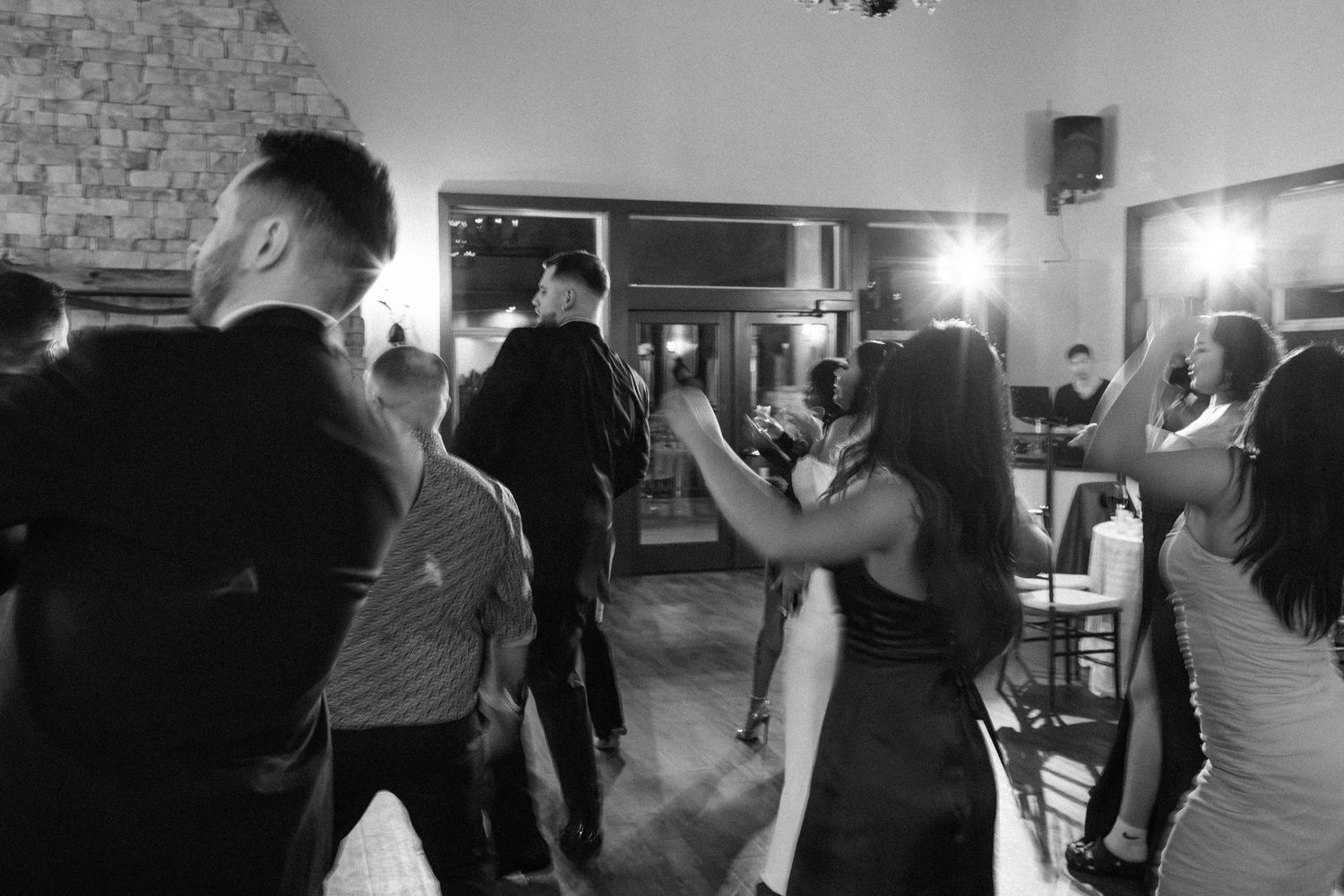 Black and white photo of guests dancing at an elegant indoor wedding reception venue.