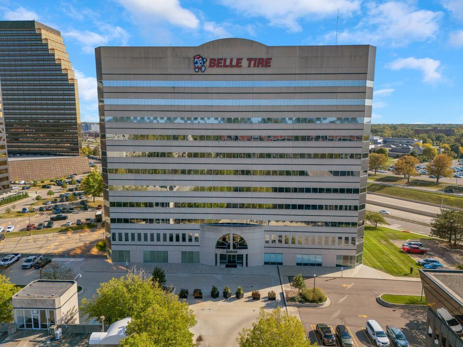 Close-up aerial view of the Belle Tire corporate headquarters glass office tower with parking lot.