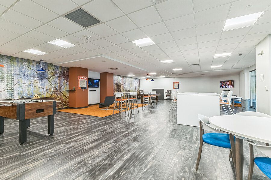 Modern office break room with foosball table, dining area, hardwood floors, and colorful wall mural.