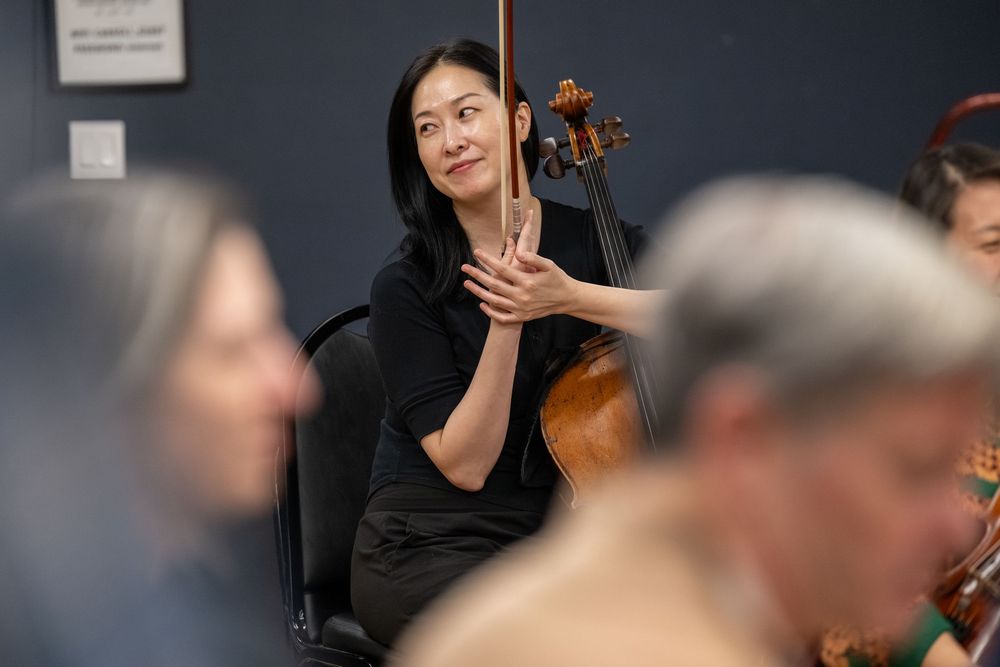 Female cellist holding her instrument during an orchestra rehearsal session.